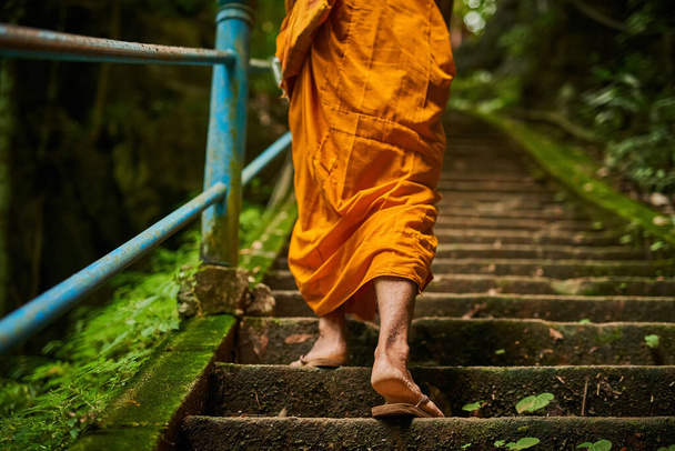 El camino hacia la iluminación tiene muchos pasos. Vista trasera de un monje budista subiendo un tramo de escalones de piedra. - Foto, imagen