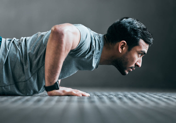 Forward focus. Cropped shot of a handsome young male athlete doing pushups against a grey background. - Foto, Imagem