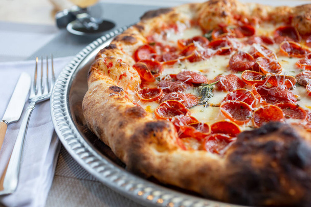 A closeup view of a rustic pizza pie, featuring toppings as pepperoni. - 写真・画像