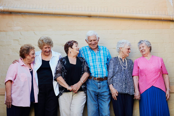 Plus on vieillit, plus on aime la vie. Vue d'un groupe de personnes âgées debout contre un mur à l'extérieur. - Photo, image