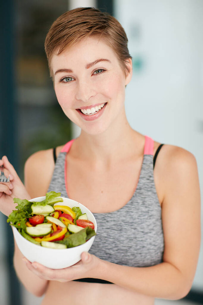 Saudável é a melhor decisão que tomei. Retrato de uma jovem mulher em forma comendo uma tigela de salada. - Foto, Imagem