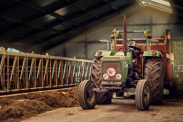 Vieux fidèles. Tourné d'un vieux tracteur rouillé debout dans une grange vide. - Photo, image