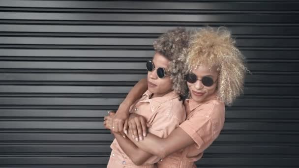 Modne Afroamerykanki siostry z blond afro fryzury przytulanie i cieszyć się razem - Materiał filmowy, wideo