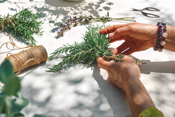 Alternative medicine. Collection and drying of herbs. Woman holding in her hands a bunch of rosemary. Herbalist woman preparing fresh scented organic herbs for natural herbal methods of treatment. - Valokuva, kuva