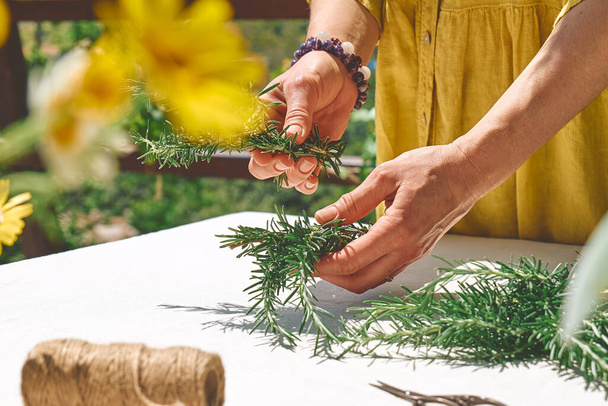 Alternative medicine. Collection and drying of herbs. Woman holding in her hands a bunch of rosemary. Herbalist woman preparing fresh scented organic herbs for natural herbal methods of treatment. - Foto, Imagen