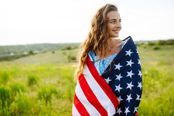 Young woman proudly hold waving american USA flag on blooming meadow.  4th of July. Fourth of July. Freedom. Patriotic holiday. Independence Day. - Φωτογραφία, εικόνα