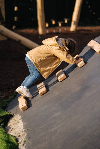 Little girl climbs up the hill on playground. Lot of enegry - Photo, Image