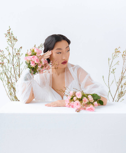 Beautiful asian with flowers on a white background close up - Photo, Image