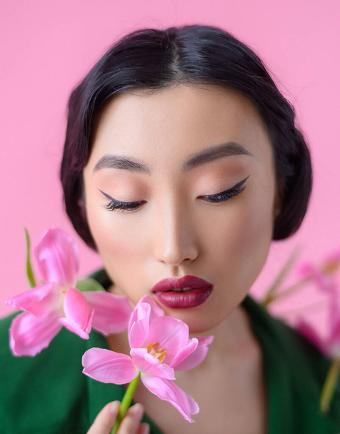 Close up portret pięknej chińskiej kobiety ze świeżymi różowymi tulipany - Zdjęcie, obraz