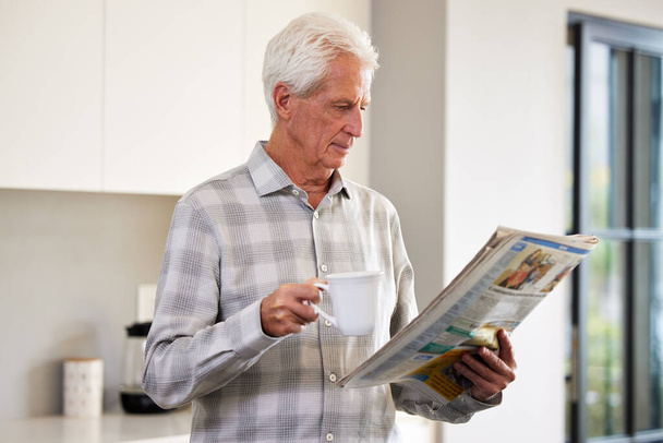Dame un periódico y un poco de té y estoy feliz. Fotografía de un hombre maduro leyendo un periódico. - Foto, imagen