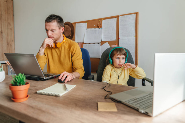 Little 5 years old girl with her father using laptops sitting at the table. Family using technology at home. Parenthood during covid-19 lockdown. Daddy with her daughter working at home. Selective focus. - Fotografie, Obrázek