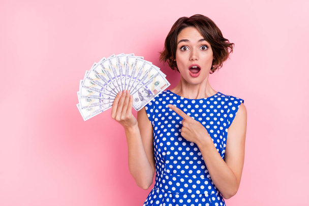 Photo of impressed young brunette lady indicate money wear blue blouse isolated on pink color background - Photo, image