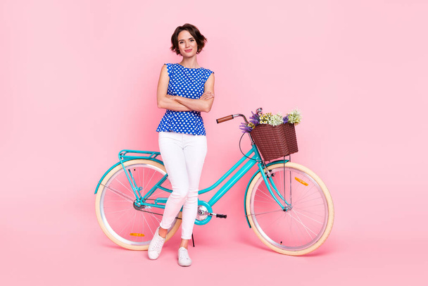 Full body photo of boss young lady ride bicycle crossed arms wear blouse pants sneakers isolated on pink background - Photo, image