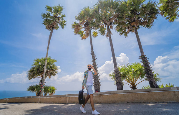 Young traveler man at summer holiday vacation with beautiful palms and seascapes at background - Fotó, kép
