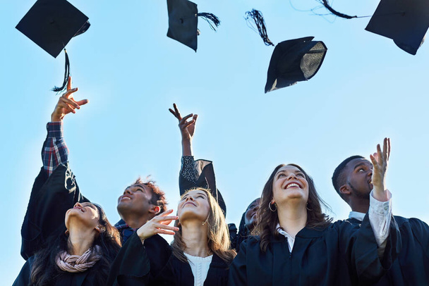 We did it. Shot of a group of students throwing their hats in the air on graduation day. - Foto, Imagem