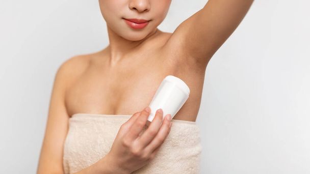 Mujer asiática joven utilizando la aplicación de desodorante en el baño - Foto, imagen