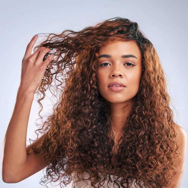 What should I do with my hair today. Cropped portrait of an attractive young woman posing in studio against a grey background. - Foto, Imagem