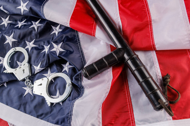 銀製の金属製の手錠とフラット表面上の米国の旗の上の警察のナイトスティック - 写真・画像