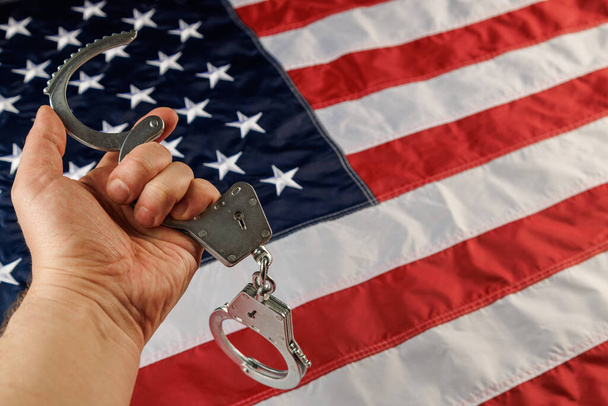 Кавказька рука з металевими наручниками срібла над прапором США. - Фото, зображення