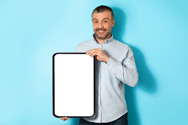 Middle Aged Man Holding Big Digital Tablet On Blue Background - Foto, afbeelding