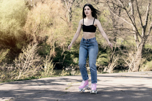 brunette woman with jeans and sports bra skating - Foto, Bild