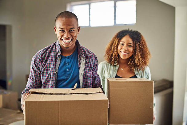 Time to start packing. Portrait of a cheerful young couple carrying boxes together to move into their new home inside during the day. - Foto, Imagen