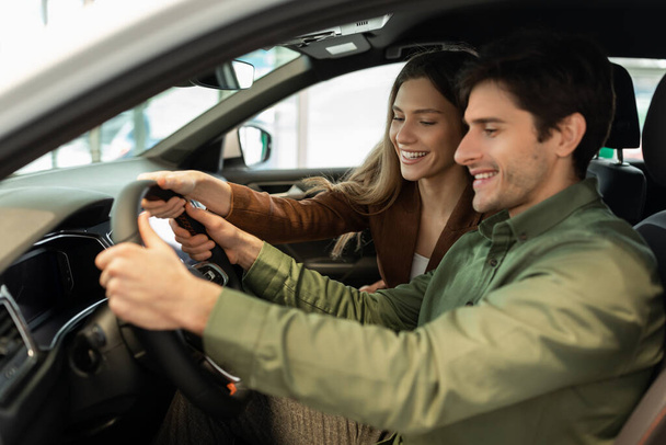 Позитивні молоді подружжя купують нову машину, сидячи всередині сучасного авто, йдуть на тест-драйв у дилерському центрі, вільне місце
 - Фото, зображення
