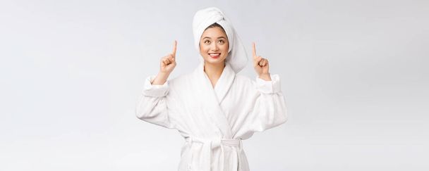 Schönheitsporträt einer jungen Frau, die mit dem Finger auf leeren Kopierraum zeigt, asiatische Schönheit im Bademantel. - Foto, Bild