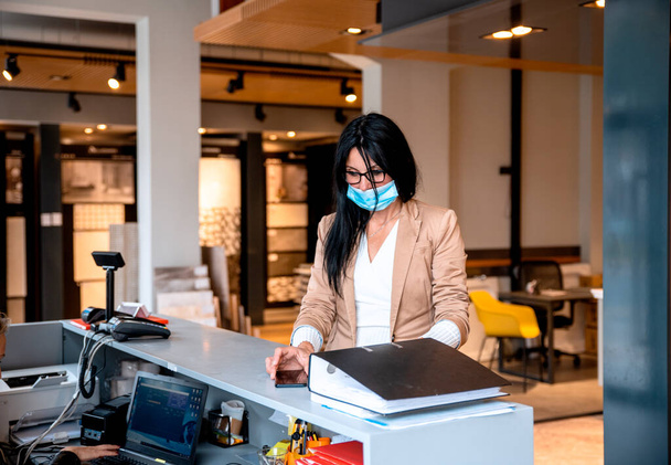 νεαρή γυναίκα με προστατευτική μάσκα στο γραφείο - Φωτογραφία, εικόνα