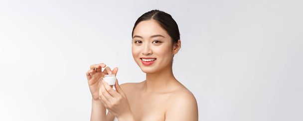 Beautiful young woman on white isolated background holding cosmetic face cream, asian - Fotografie, Obrázek