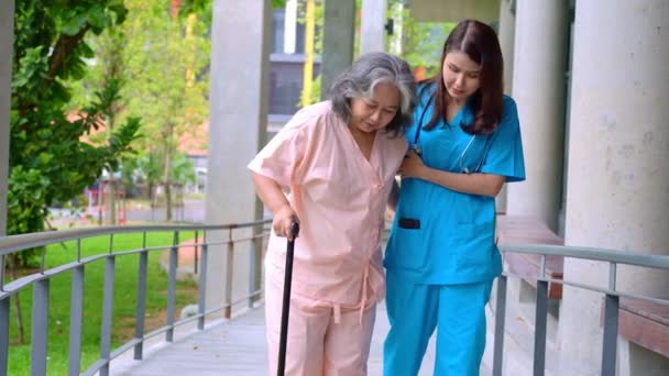 Doctor help old elderly Asian woman uses a walker and walking for physical therapy in the hospital.  Concept of happy retirement With care from a caregiver and Savings and senior health insurance - Filmati, video