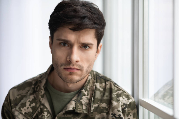 Closeup portrait of upset soldier standing by window - Valokuva, kuva