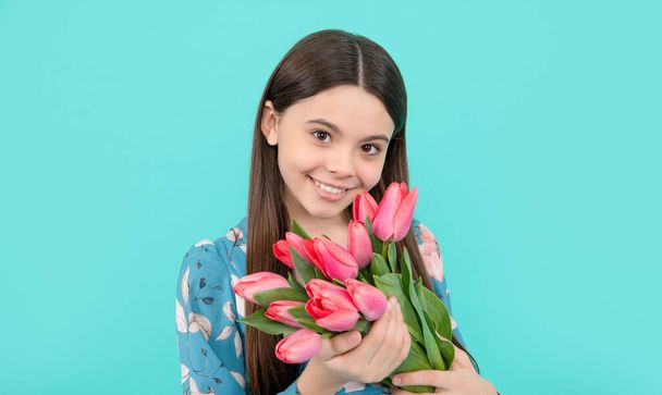 teen girl with spring bouquet on blue background. floral present. happy child enjoy tulips. - Фото, изображение