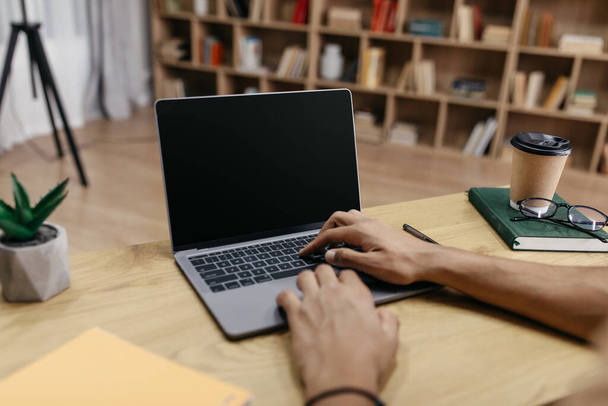 Homem irreconhecível trabalhando no computador portátil com tela preta em branco, digitando no teclado, mockup - Foto, Imagem