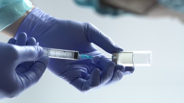 Lääkäri käyttää lääketieteellisiä käsineitä täyttää ruiskun rokotteella lasisesta injektiopullosta. Pystysuora video, 4k - Materiaali, video
