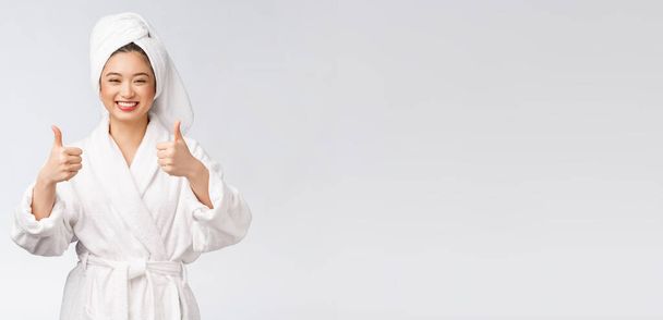 Mooie aziatische vrouw perfecte huid tonen duimen omhoog geïsoleerd op witte achtergrond. - Foto, afbeelding