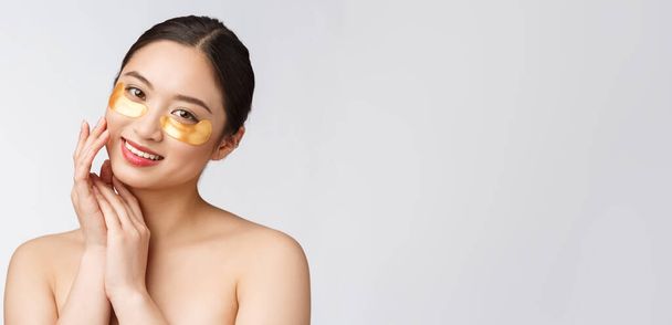 Asiatische Schönheit Teenager Frau pflegen ihre Haut mit goldenen Augenmasken Flecken unter den Augen - Foto, Bild