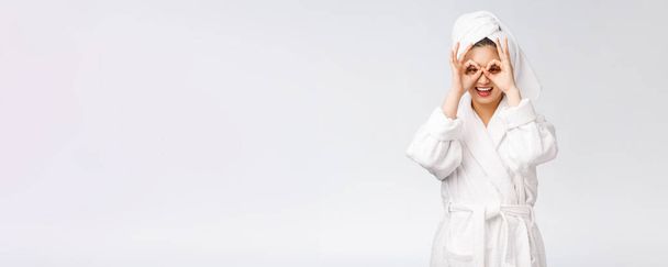 Gros plan de jeune femme souriante avec doigt ok geste sur les yeux, isolé sur fond blanc
 - Photo, image