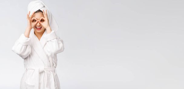 Gros plan de jeune femme souriante avec doigt ok geste sur les yeux, isolé sur fond blanc
 - Photo, image