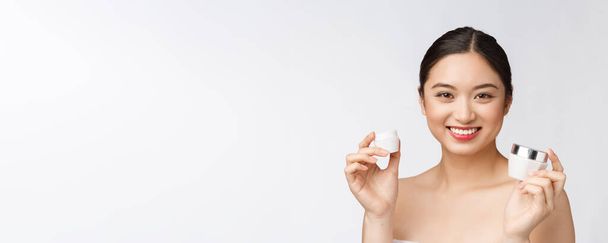 bela jovem mulher no branco isolado fundo segurando cosmético rosto creme asiático
 - Foto, Imagem