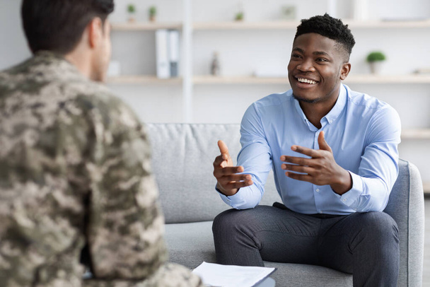 Psicólogo afroamericano positivo conversando con soldado - Foto, Imagen