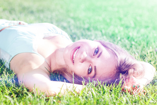 Pretty brunette girl wearing elegant dress relaxing outdoor in green grass and smells aromatic lemon or lime citrus - Foto, immagini