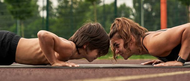 Side view of european mother and son doing plank - Fotoğraf, Görsel