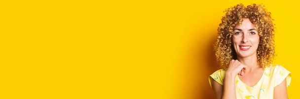 smiling beautiful curly young woman on a yellow background. Banner - Fotó, kép