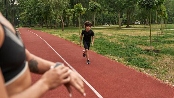 Female trainer note time on smartwatch of run boy - 写真・画像