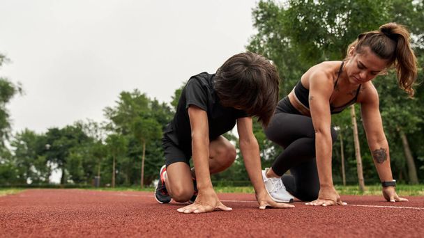 Athletic mother and son on start before running - 写真・画像