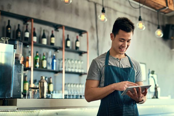 Řídí své obchody online. Vystřižený záběr mladého muže pracujícího na tabletu ve své kavárně. - Fotografie, Obrázek