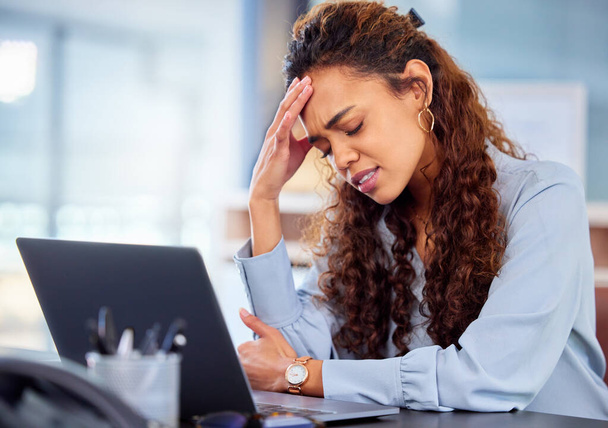 To trochę zniechęcające. Przycięte ujęcie atrakcyjnej młodej bizneswoman cierpiącej na ból głowy podczas pracy na laptopie w biurze. - Zdjęcie, obraz