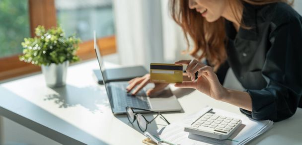 Κοντινό πλάνο του κοριτσιού κατέχουν τραπεζική πιστωτική κάρτα και τον τύπο στο laptop, online αγορές χρησιμοποιώντας υπολογιστή, την αγορά αγαθών ή την παραγγελία σε απευθείας σύνδεση, την εισαγωγή τραπεζικών λογαριασμών και λεπτομέρειες σε απευθείας σύνδεση τραπεζική προσφορά. - Φωτογραφία, εικόνα