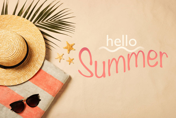 Hello Summer. Beach towel, sunglasses, hat, palm leaf and starfishes on sand, flat lay - Foto, afbeelding